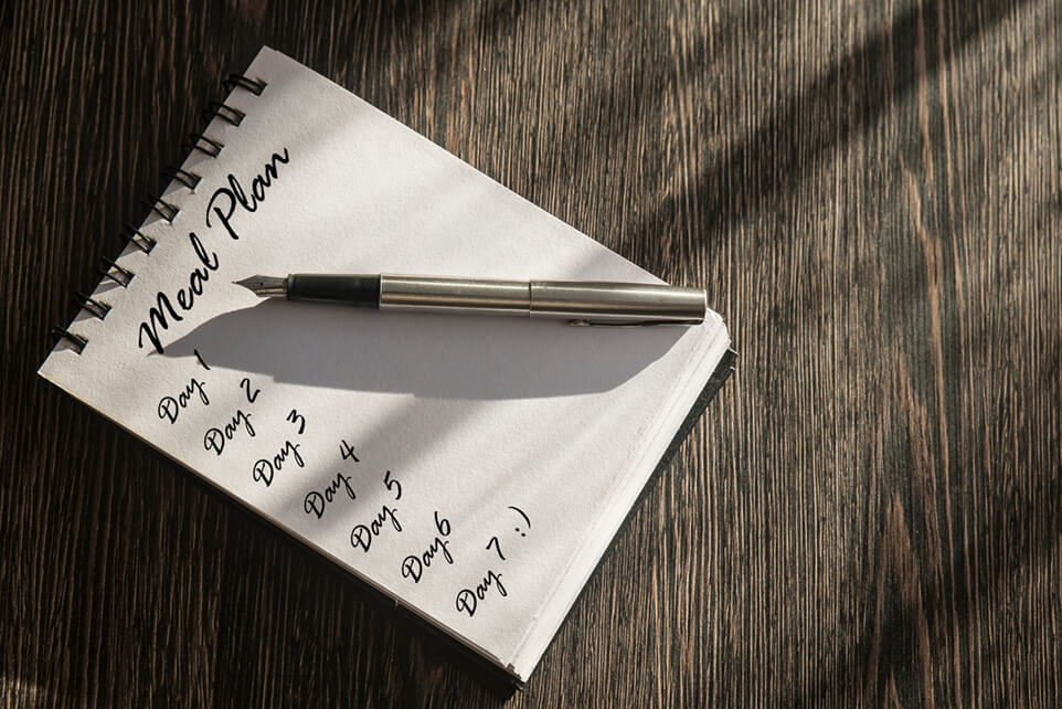 Notatnik kuchenny zawierający przykładowy jadłospis, który pomaga zaplanować tanie i zbilansowane posiłki na cały tydzień.